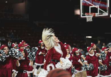 Cheerleaders in christmas outfits on a basketball court.