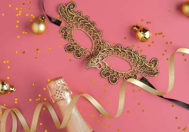 Gold masquerade mask on pink background.