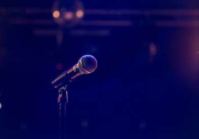 Microphone on stage with purple lighting.