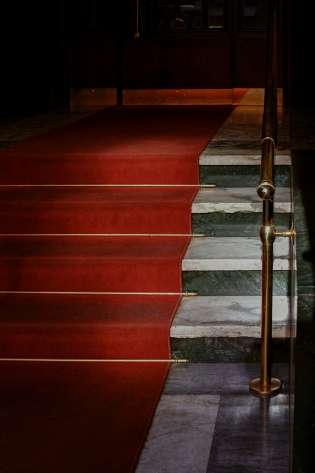 Red carpet leading up marble stairs.