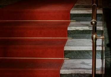 Red carpet leading up marble stairs.