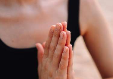 Person meditating with palms touching.