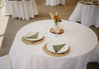 Round table with white tablecloth and two plates .
