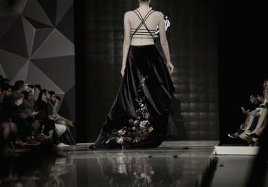 Greyscale image of a model in a dress on a runway.