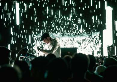 Man playing the drums on a stage with an audience in front.