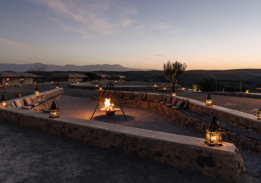 Bonfire in desert setting with stone seating.