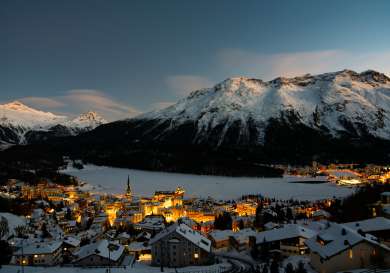 Dusk by the frozen St. Moritz Lake in Switzerland and the neighbouring lit up city.