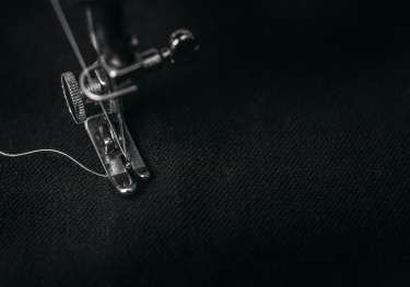 Sewing machine stitching on black fabric.