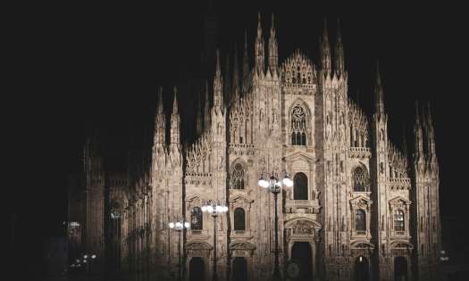Duomo Catherdral in Milan at night with street lights in front.