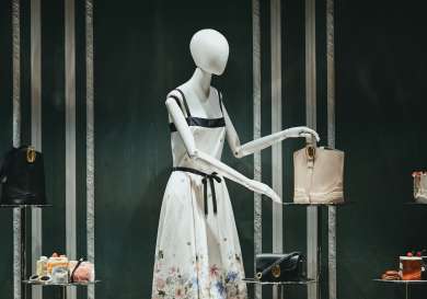 Mannequin in a dress surrounded by luxury bags.