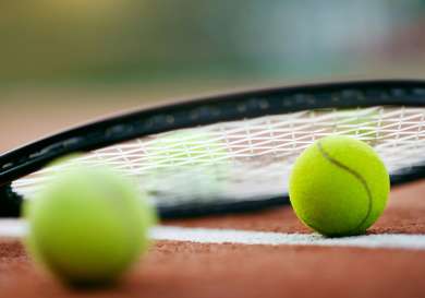 Tennis racket on two tennis balls .