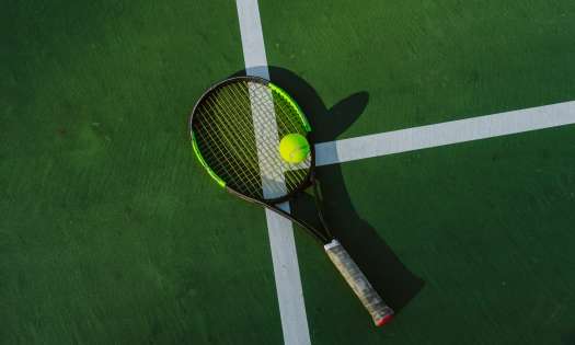 Tennis racket on green court.