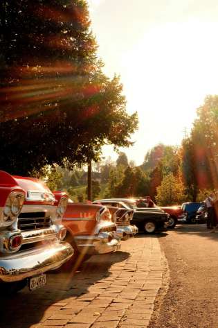 Vintage cars on a stone road with the sun shining.