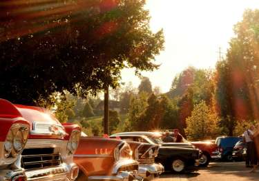 Vintage cars on a stone road with the sun shining.