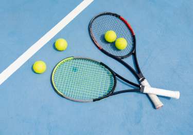 Two crossed tennis rackets on blue tennis court.
