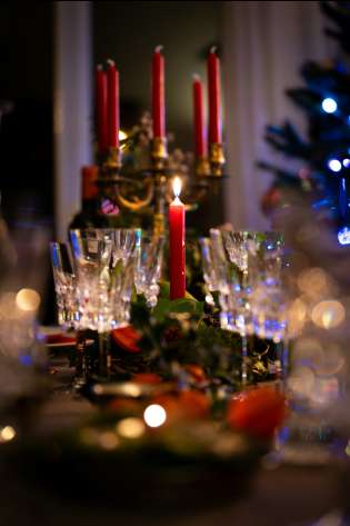 Table with champagne glasses and red candles on it.