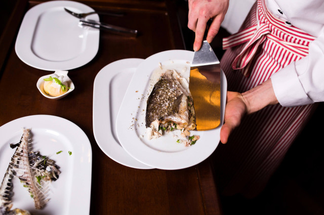 person serving fish on plate