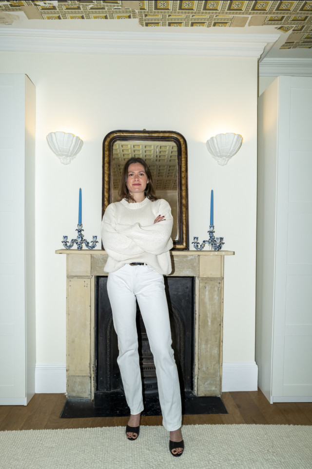 portrait of woman posing in white outfit in front of fireplace
