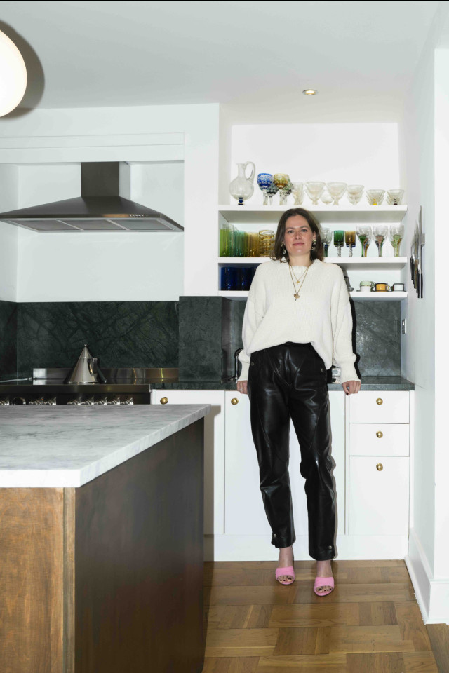 portrait of woman posing in kitchen with white top and leather trousers