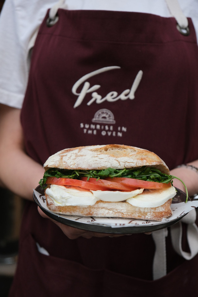 person holding freshly-made sandwich