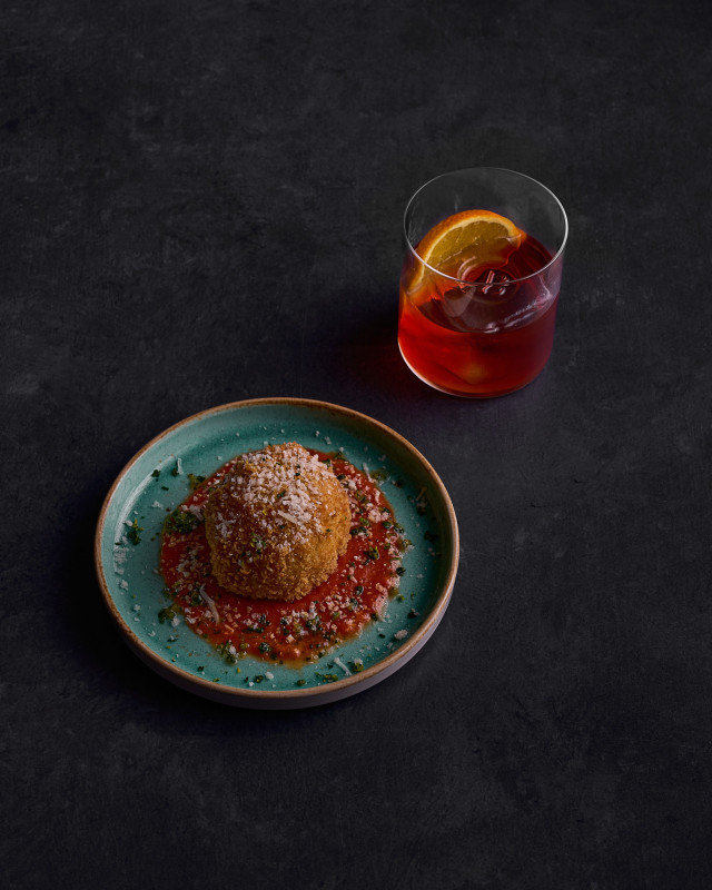 cocktail arranged next to dish with tomato sauce