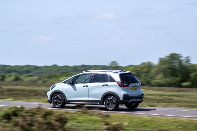 photo of honda jazz hybrid car driving along road 