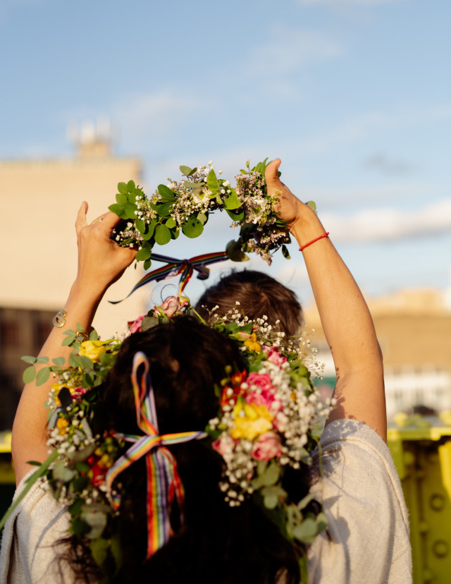 woman placing flower crown on another person's head
