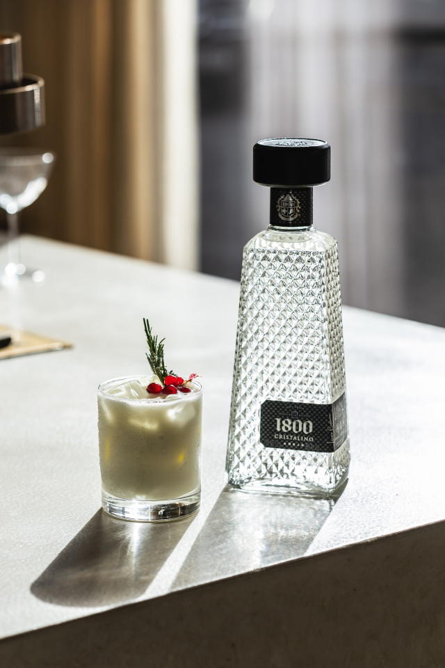 photo of coconut cocktail on ledge with bottle of alcohol 