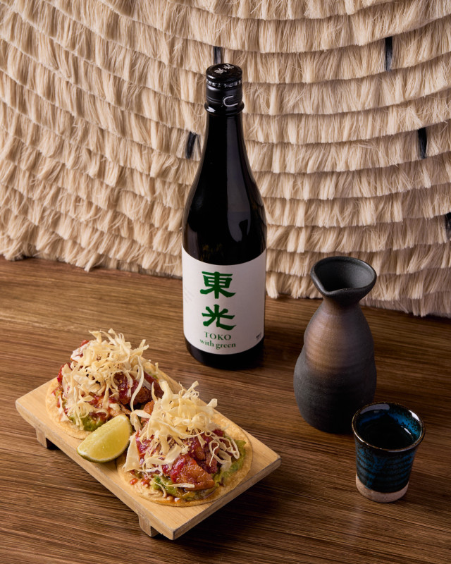 bottle of sake with side of food and wedge of lime