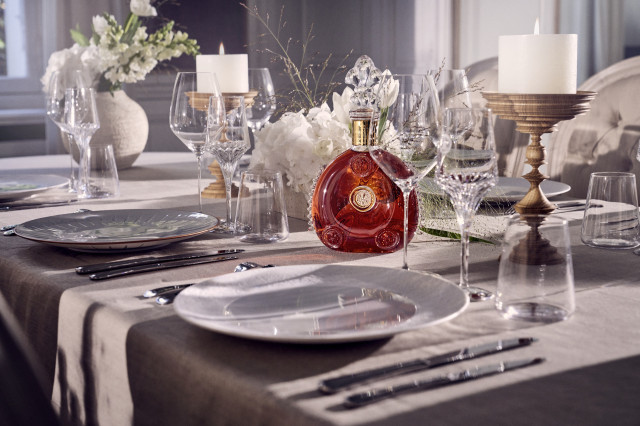 bottle of cognac on table with plates and cutlery 