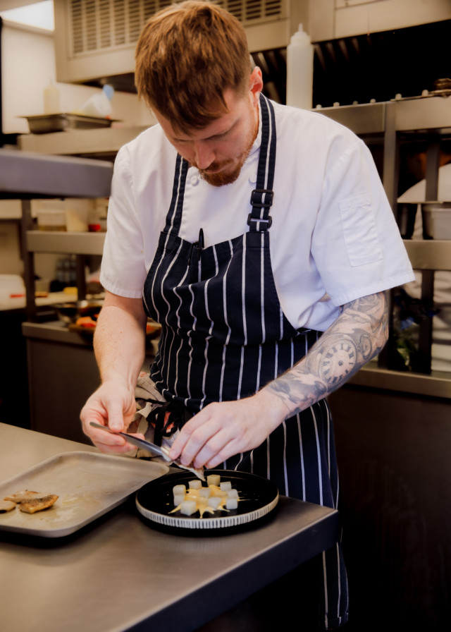 chef at work in a hotel restaurant preparing a dainty dish