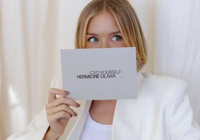 Hermione olivia holding a cue card in front of her face.