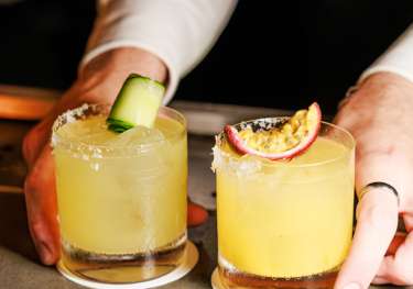 Bartender with two spicy margaritas.