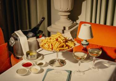 Photo of table topped with plate of chips and two glasses of champagne.