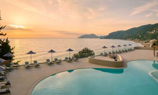 Photo of hotel pool with the sunset in the background.