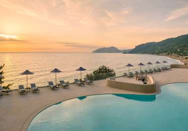 Photo of hotel pool with the sunset in the background.