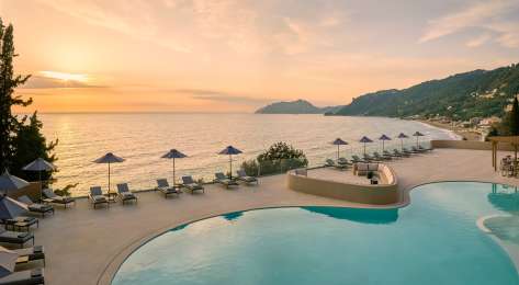 Photo of hotel pool with the sunset in the background.