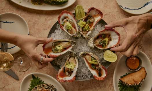 Plate of oysters with side dishes and lime slices.
