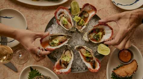 Plate of oysters with side dishes and lime slices.