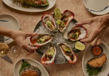 Plate of oysters with side dishes and lime slices.