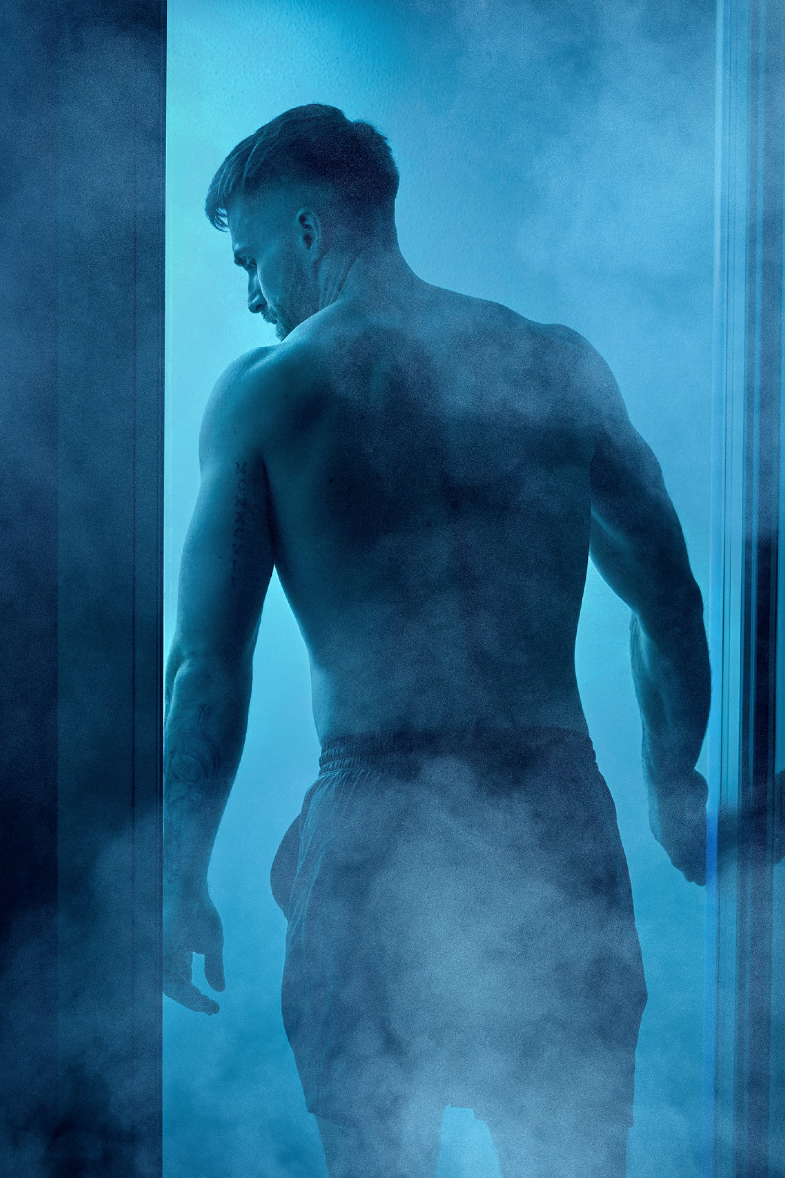 man at sauna with blue lights shining through the door 