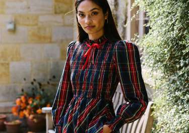 Model wearing tartan print dress with long sleeves .