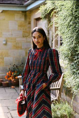 Model wearing tartan print dress with long sleeves .
