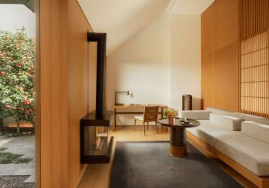 Lounge area in luxurious hotel suite with electric fire, desk, and sofa.