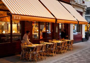 Photo of toum restaurant with striped awning .