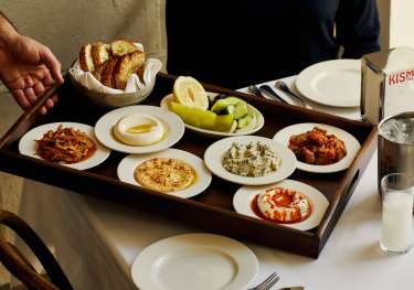 Small plates on wooden tray being served at kismet restaurant.