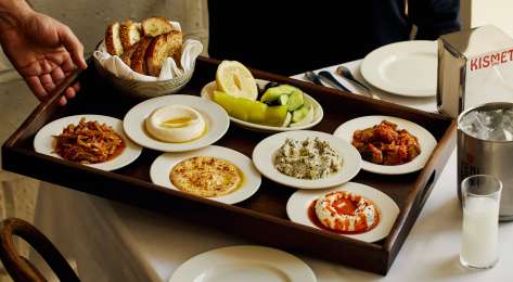 Small plates on wooden tray being served at kismet restaurant.