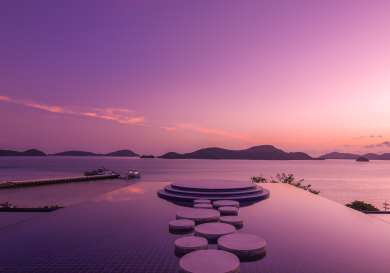 Rooftop bar area with round paving stones in a shallow pool overlooking the sea .