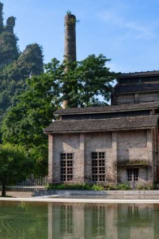 Outbuilding located next to mountain with greenery.