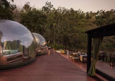 Outdoor hotel pods with elephants in the distance.